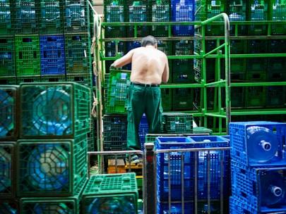 A warehouse worker organizing pallets of bottled water ready for delivery.
