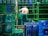 A shirtless man is organizing blue and green crates in what appears to be an industrial setting. The crates are stacked in neat rows and contain large water bottles. Metal bars and stacks of crates surround him, suggesting warehouse activity.