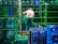 A shirtless man is organizing blue and green crates in what appears to be an industrial setting. The crates are stacked in neat rows and contain large water bottles. Metal bars and stacks of crates surround him, suggesting warehouse activity.