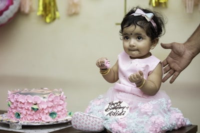 a baby girl sitting in front of a birthday cake