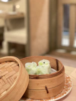 Steaming bamboo basket filled with freshly made dumplings glowing under warm light.