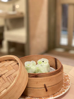 Steaming bamboo basket filled with freshly made dumplings glowing under warm light.