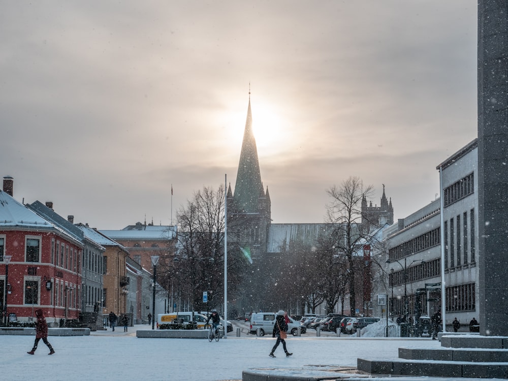 a couple of people walking across a snow covered street