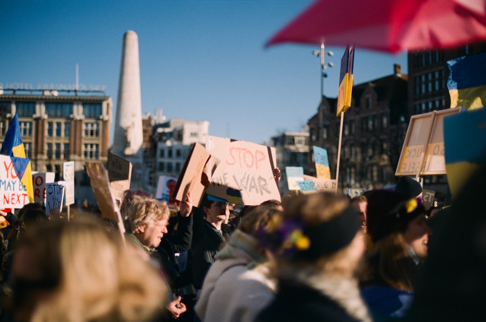 a crowd of people holding signs and umbrellas