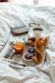 a tray of food on a bed with silverware