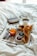 A breakfast tray on a bed featuring a cup of coffee, a glass of orange juice, a selection of pastries including croissants, two small bowls of jam, and cutlery neatly arranged. The setting is cozy and inviting, suggesting a relaxed morning atmosphere.