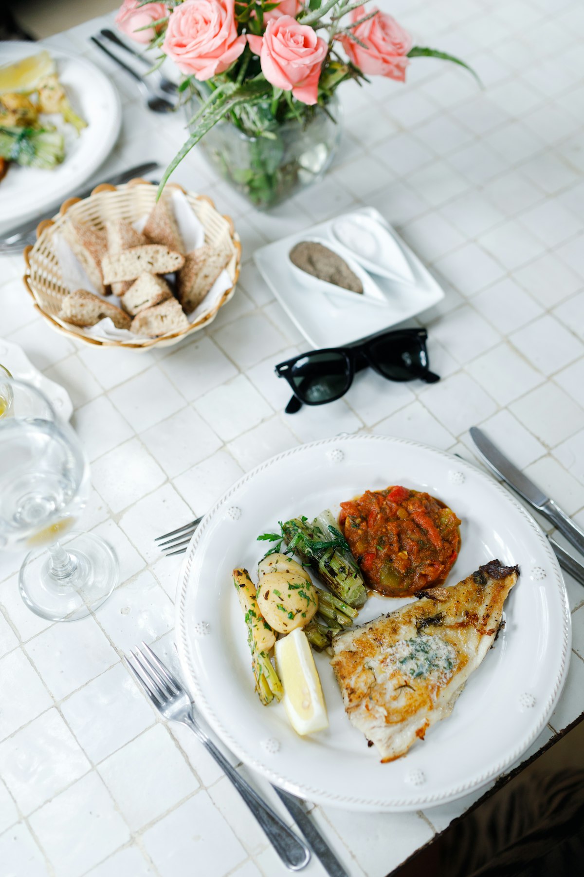 An abundant spring table setting at Sorrel — plated fish, garden vegetables, a bread basket, and fresh flowers laid out for service