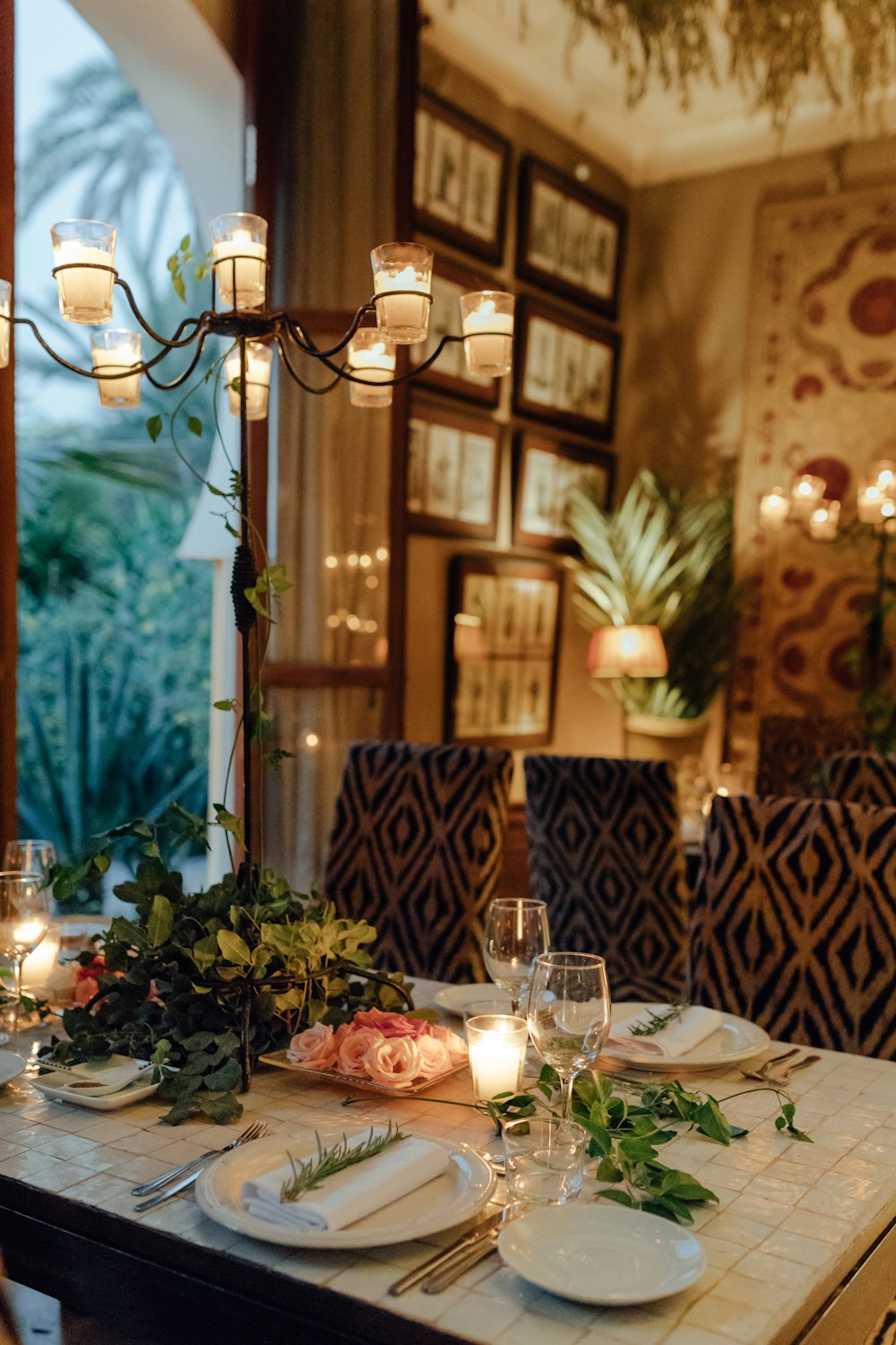 a dining room table set with place settings and candles