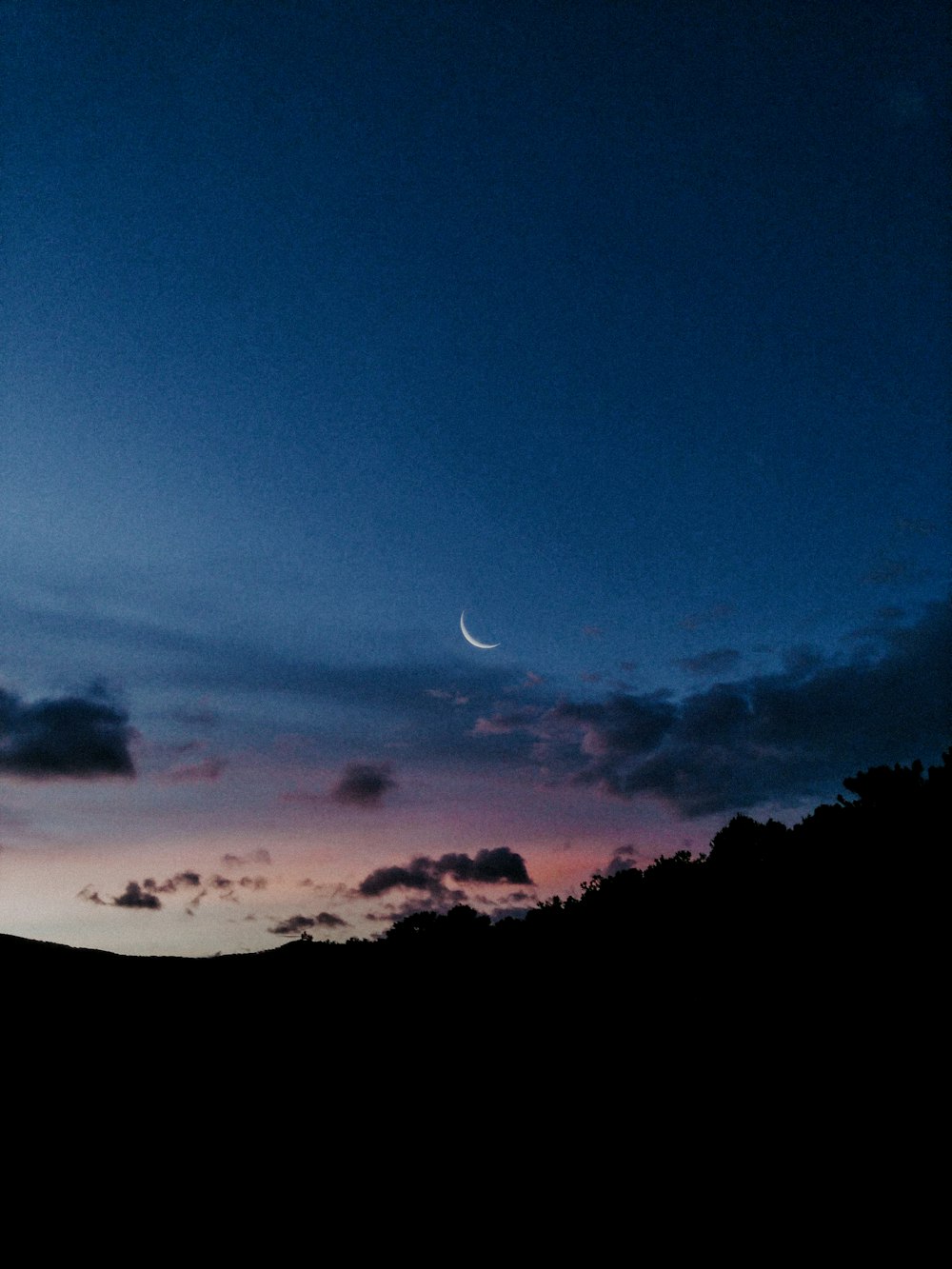uma vista do céu à noite com uma meia-lua à distância