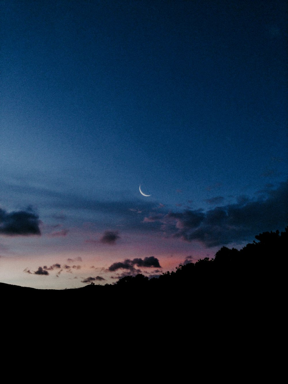 a view of the sky at night with a half moon in the distance