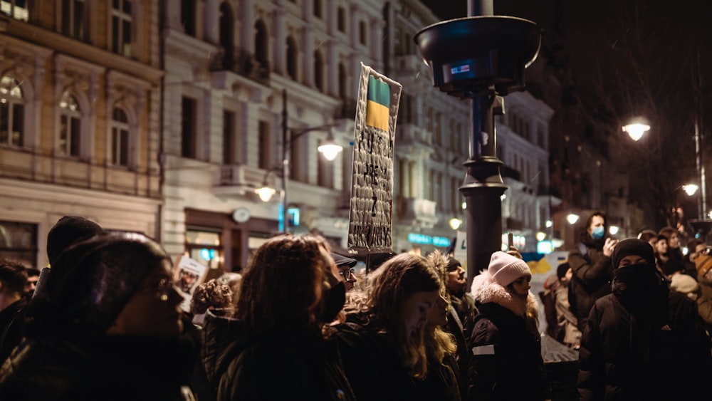 a crowd of people standing on a street at night