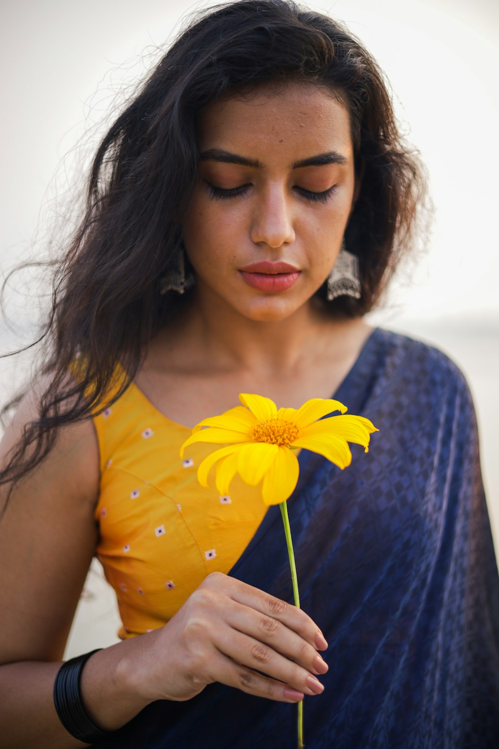 a woman holding a yellow flower in her hand