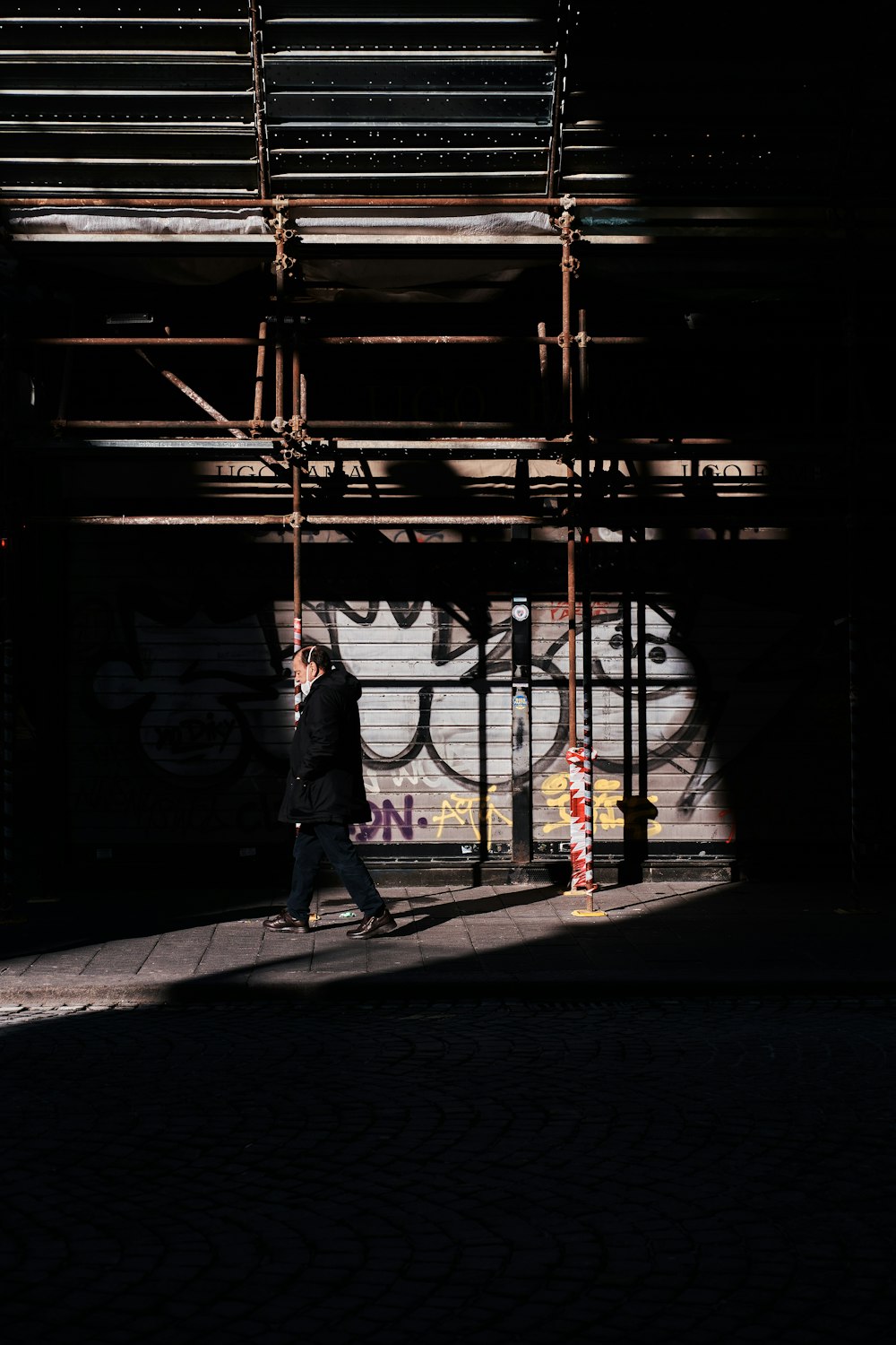 a man walking down a sidewalk next to a building