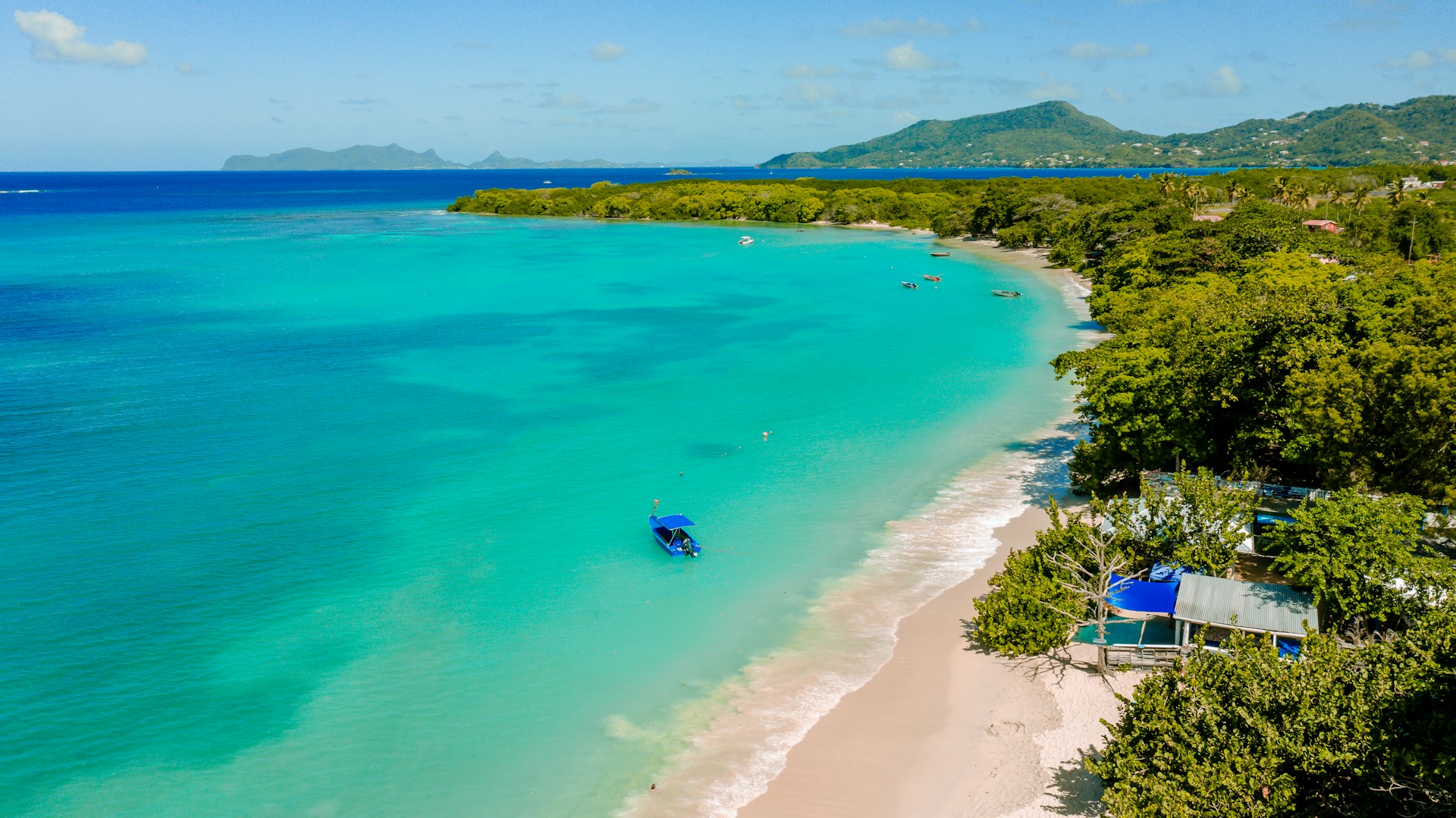 an aerial view of a beach with a boat in the water