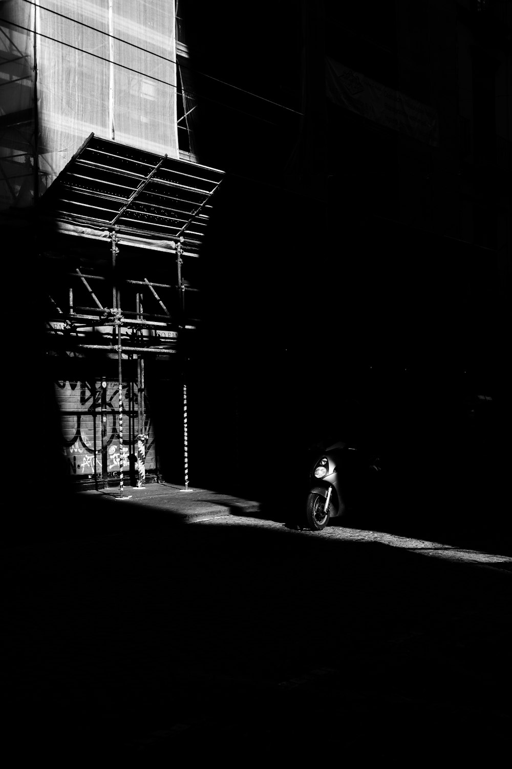 a black and white photo of a motorcycle parked in front of a building