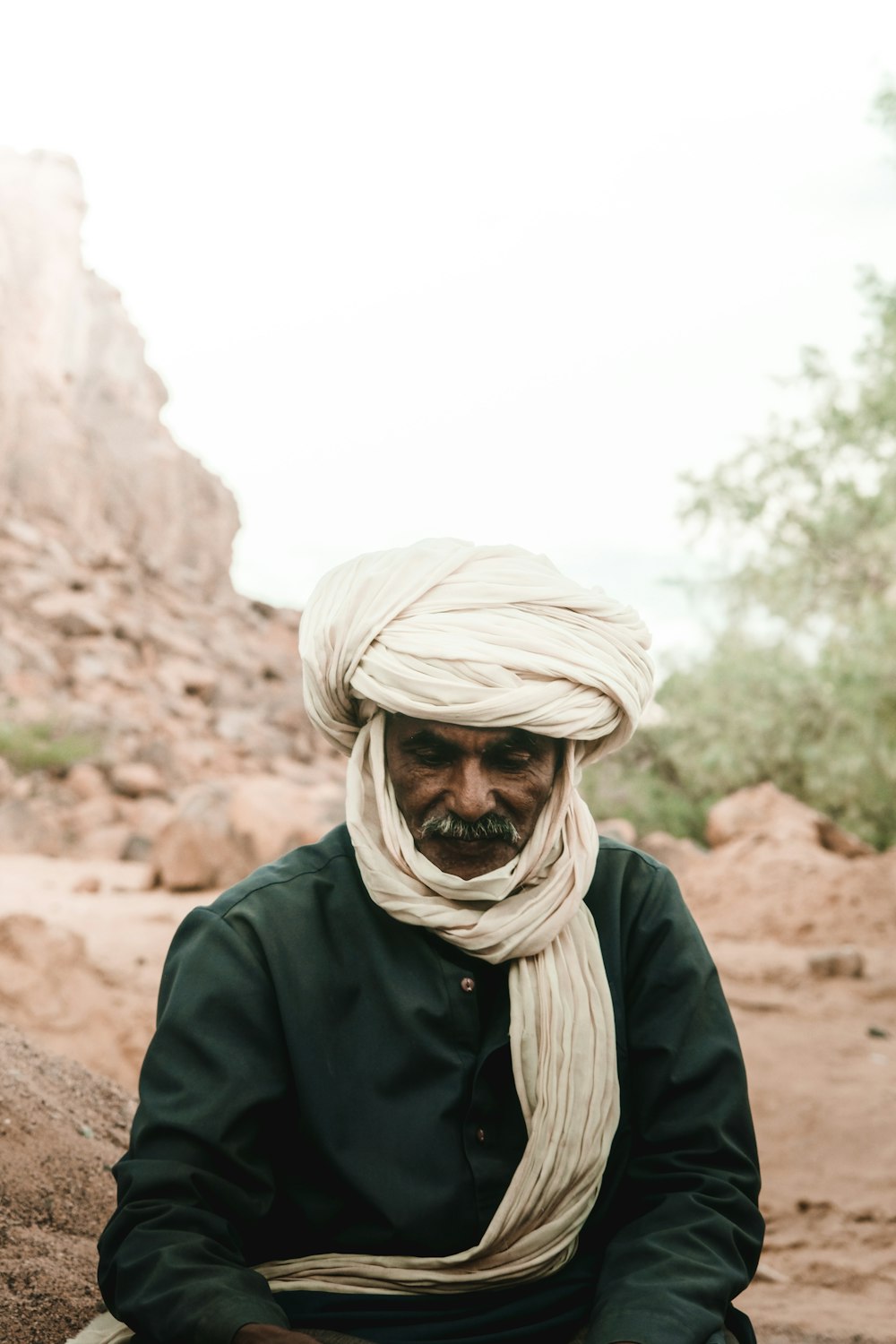 Ein Mann mit Turban sitzt auf einem Felsen