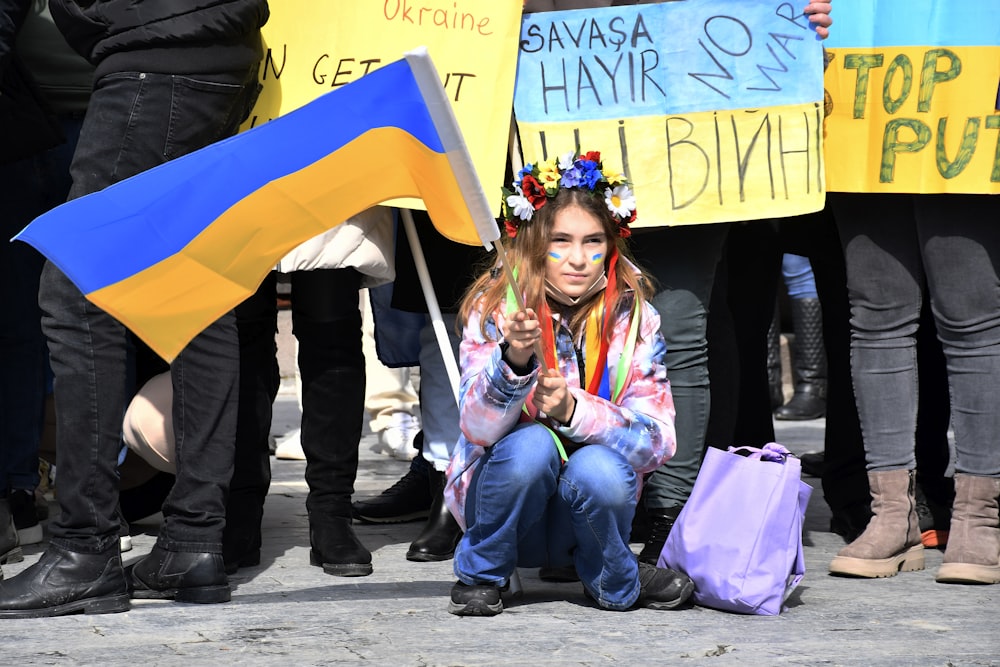 a young girl sitting on the ground holding a flag