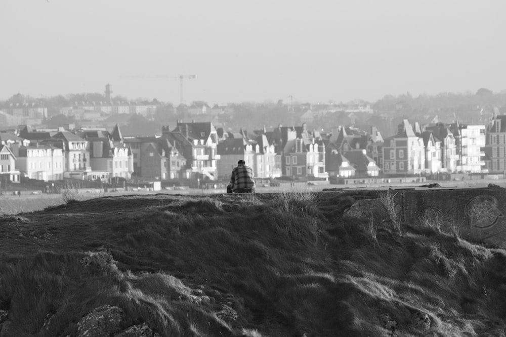 a black and white photo of a person sitting on top of a hill