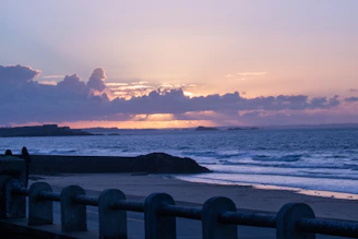 the sun is setting over the ocean on the beach