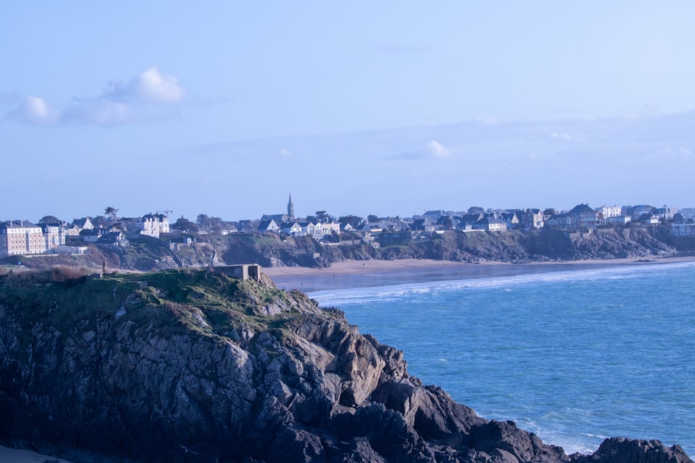 a view of a beach with houses on the cliff