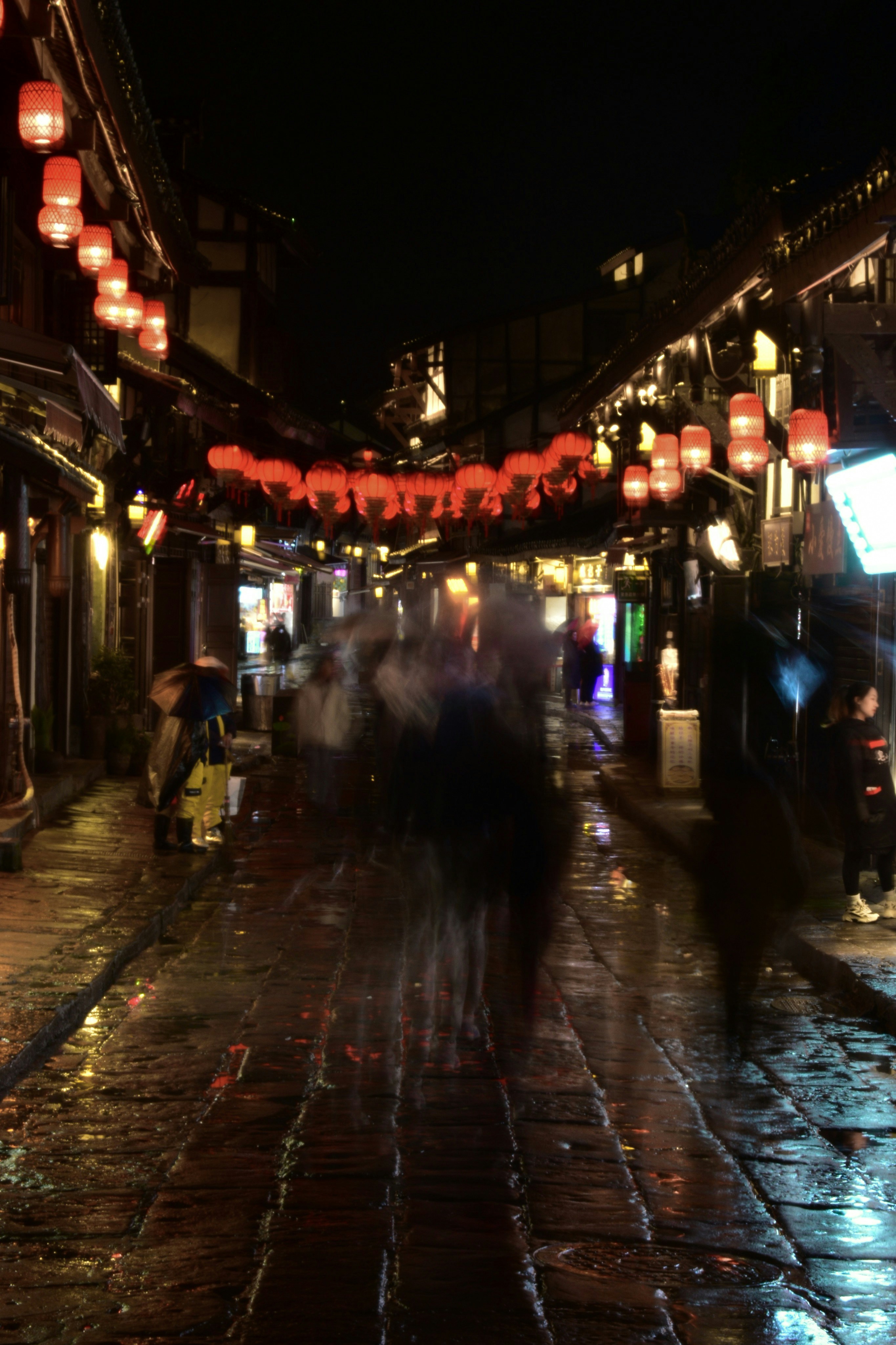 a group of people walking down a street at night