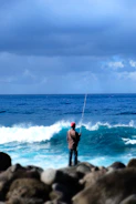 Fisherman wearing breathable, durable fishing apparel standing by the sea.