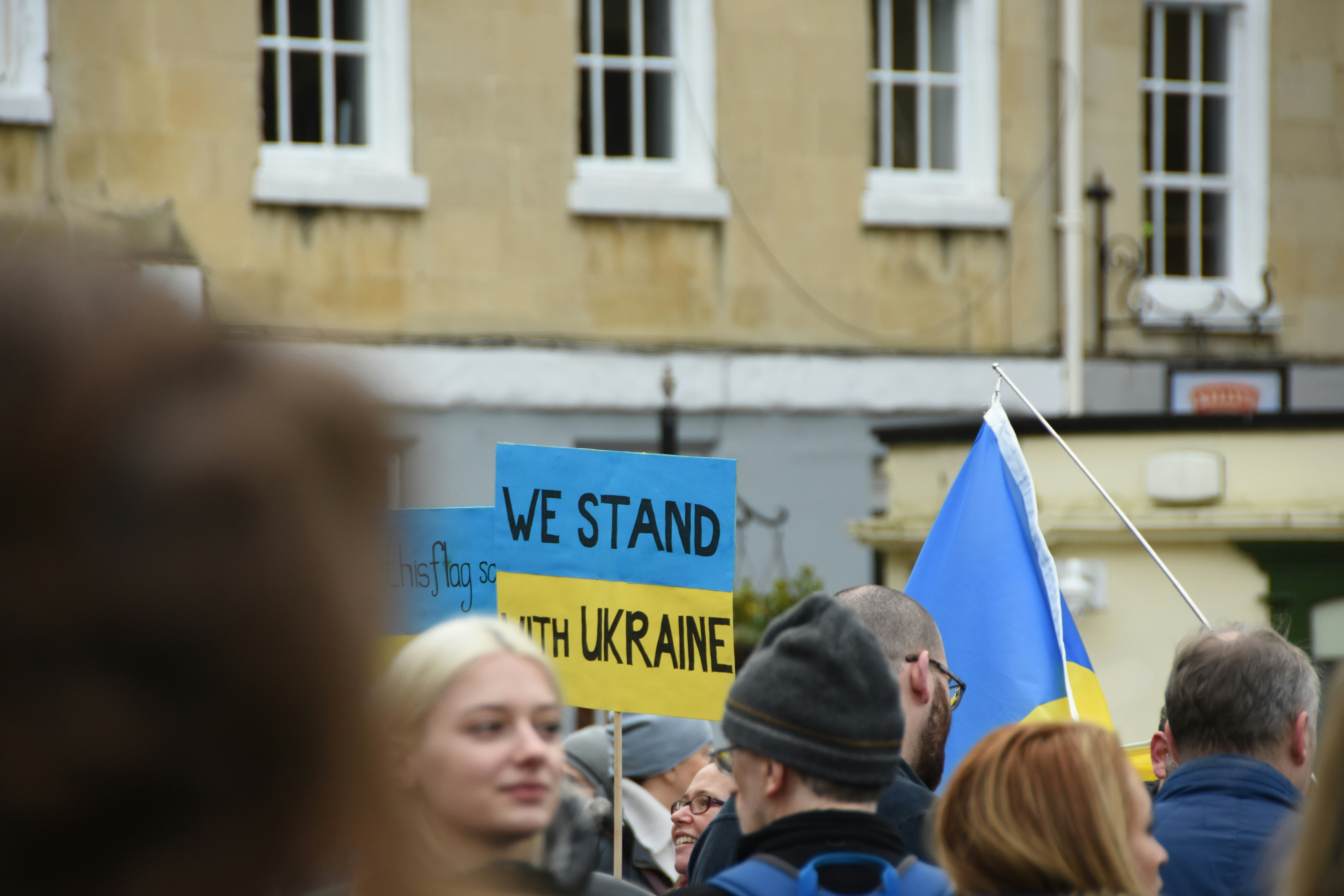 Eine Menschenmenge, die um ein blau-gelbes Schild steht
