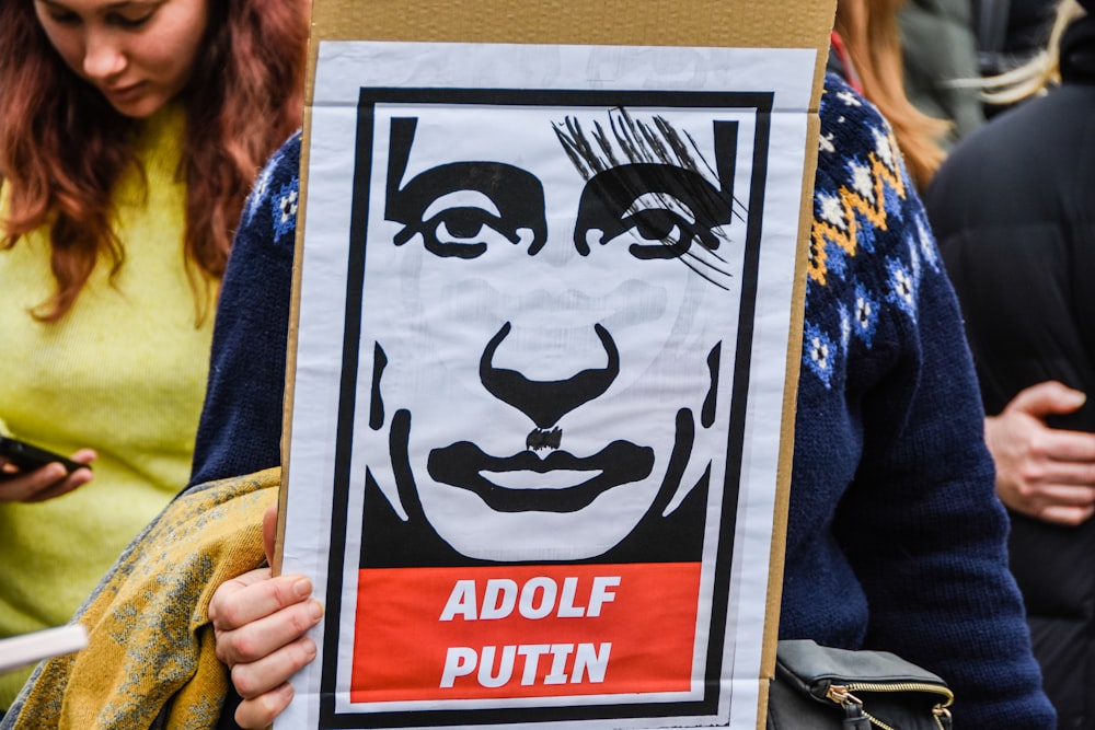 una persona sosteniendo un cartel con una imagen de la cara de un hombre en él