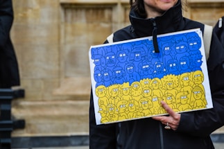 A friendly political poster designer working on a vibrant banner using the Jananeta app on a tablet.