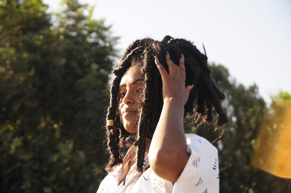 a woman with dreadlocks holding her hand up to her head