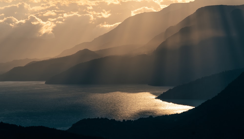 the sun shines through the clouds over a body of water