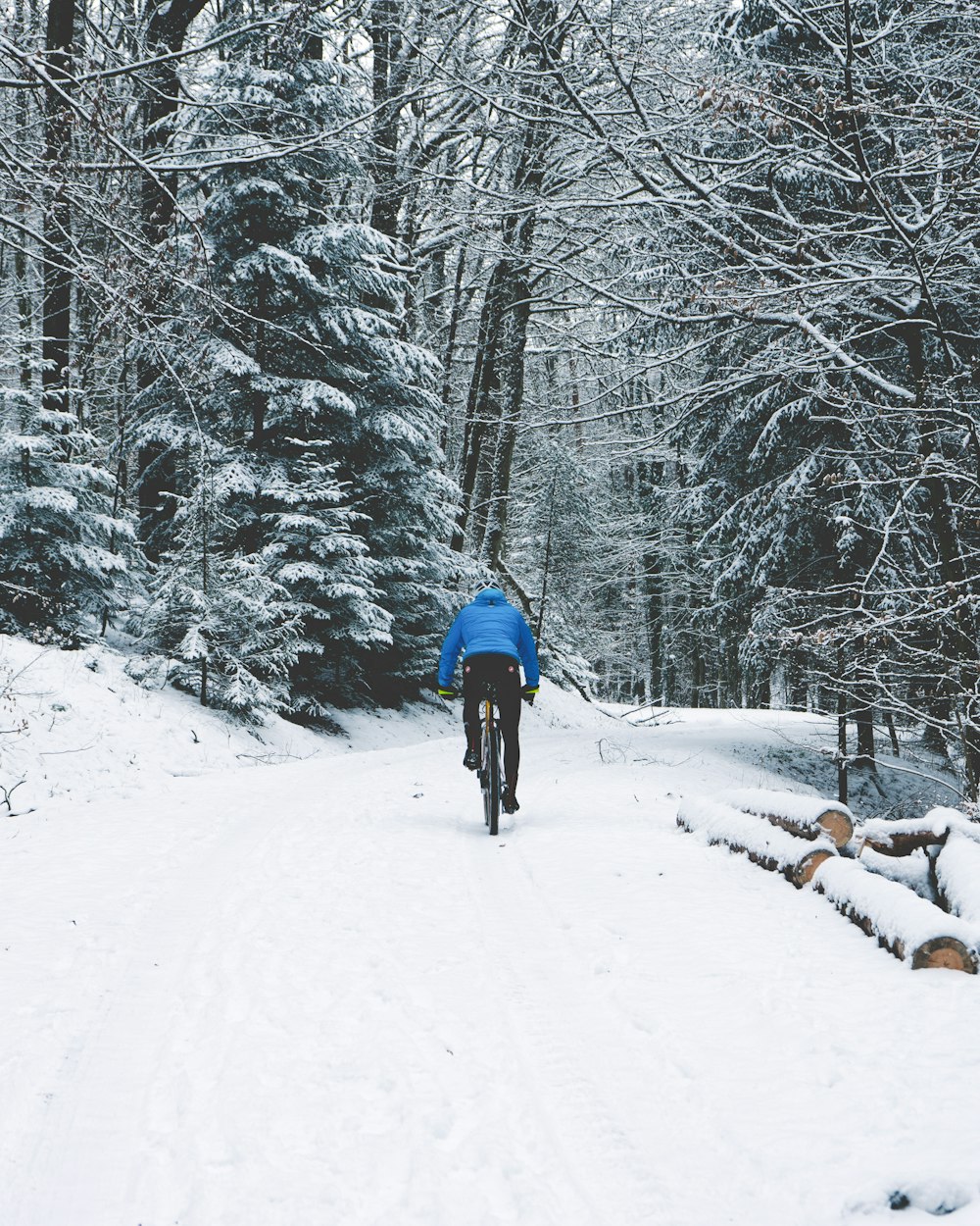 a man riding a bike down a snow covered road