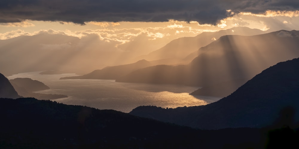 the sun is shining through the clouds over the mountains