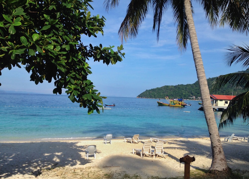 a beach with chairs and a boat in the water