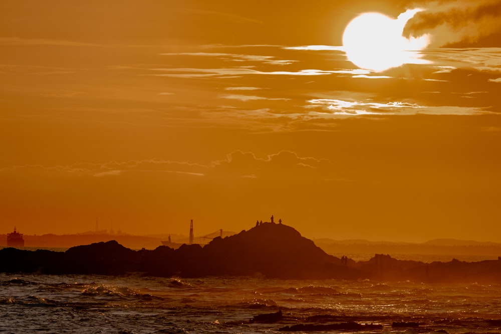 Die Sonne geht über einer felsigen Insel im Ozean unter