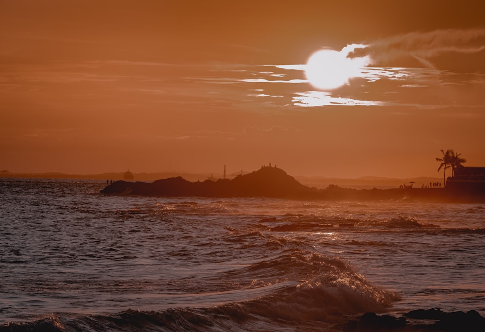 the sun is setting over the ocean with waves