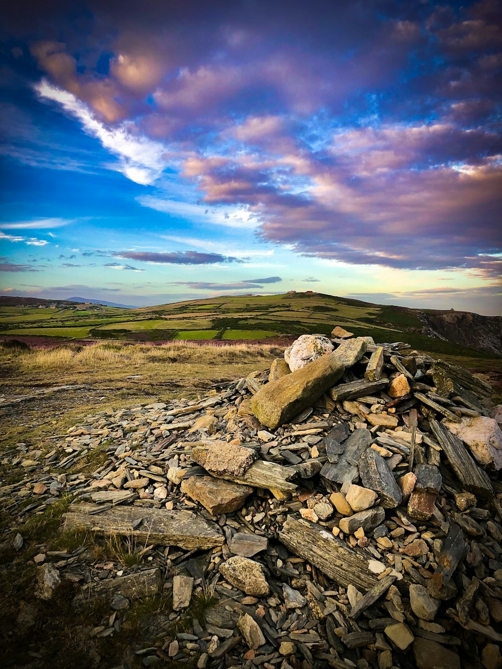 un tas de rochers assis au sommet d’un champ couvert d’herbe