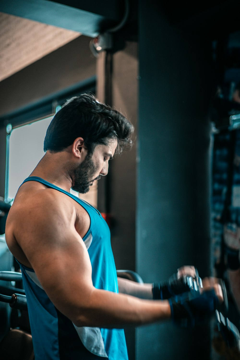 a man in a blue tank top working on a machine