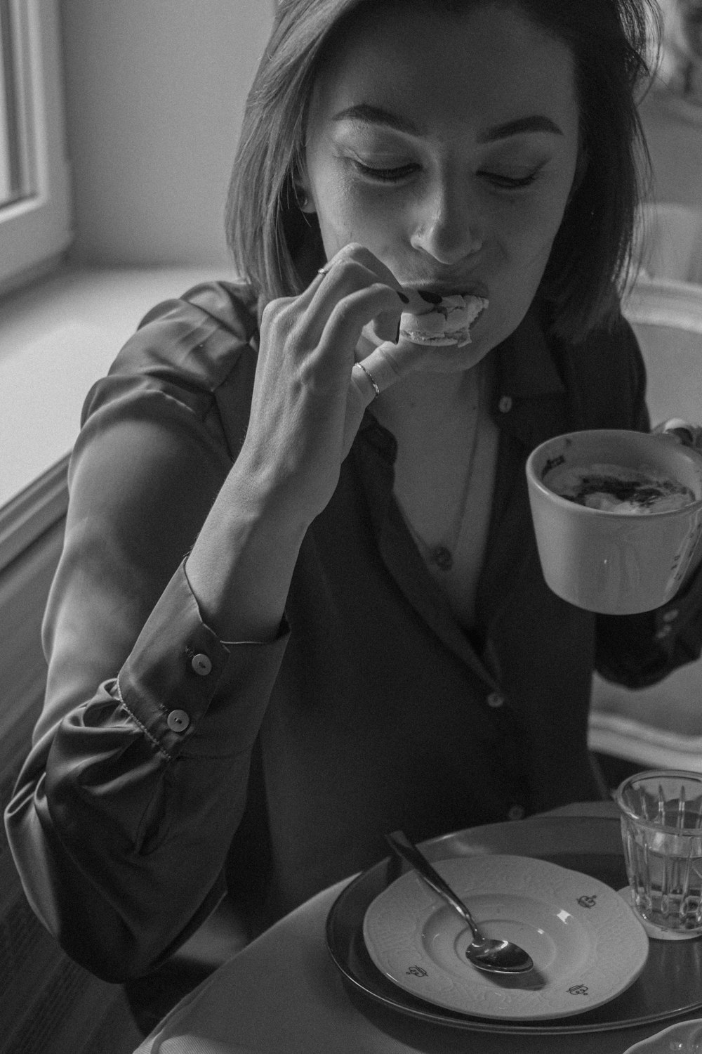 a woman sitting at a table eating a doughnut