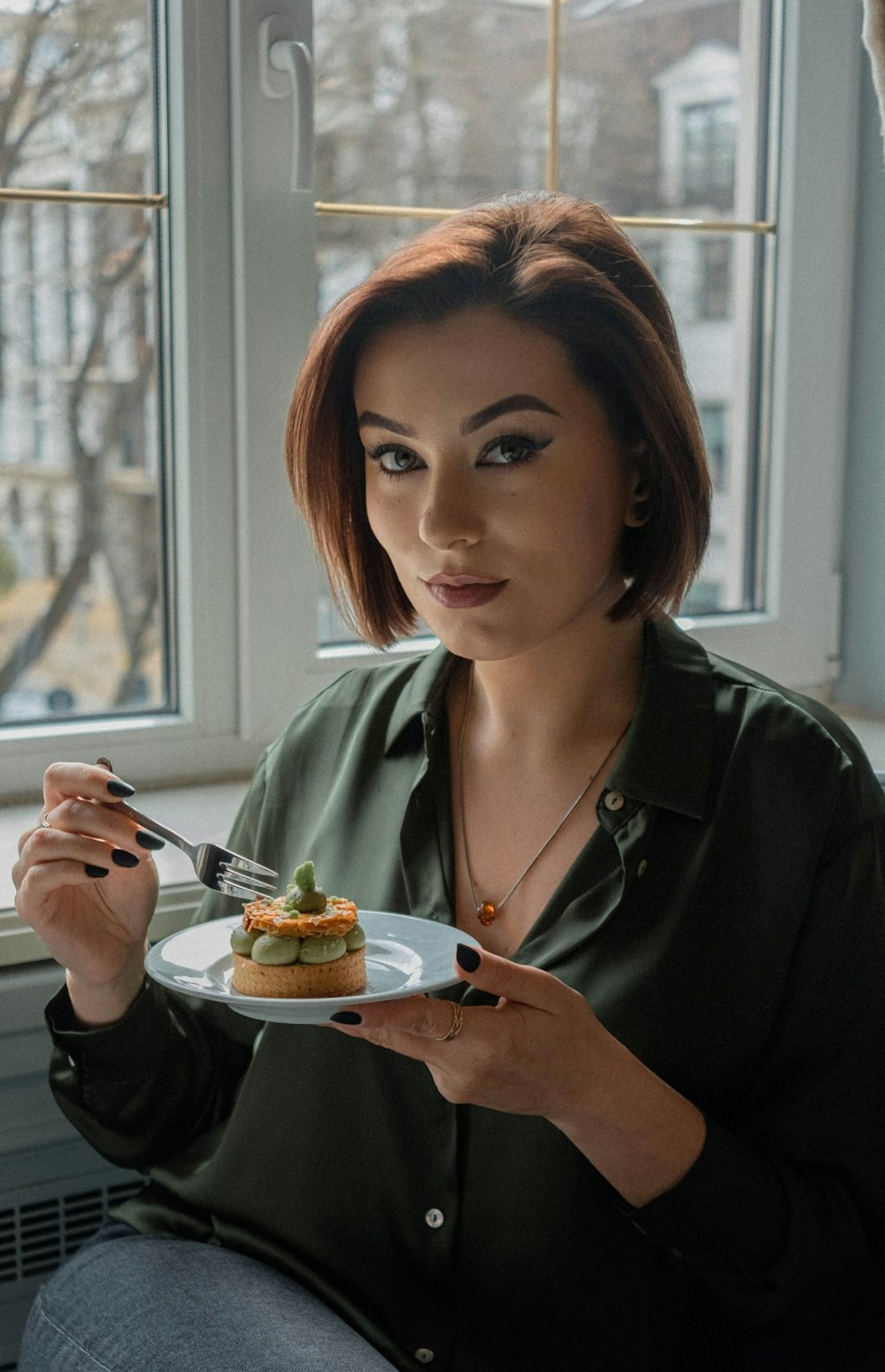 a woman holding a plate of food in front of a window