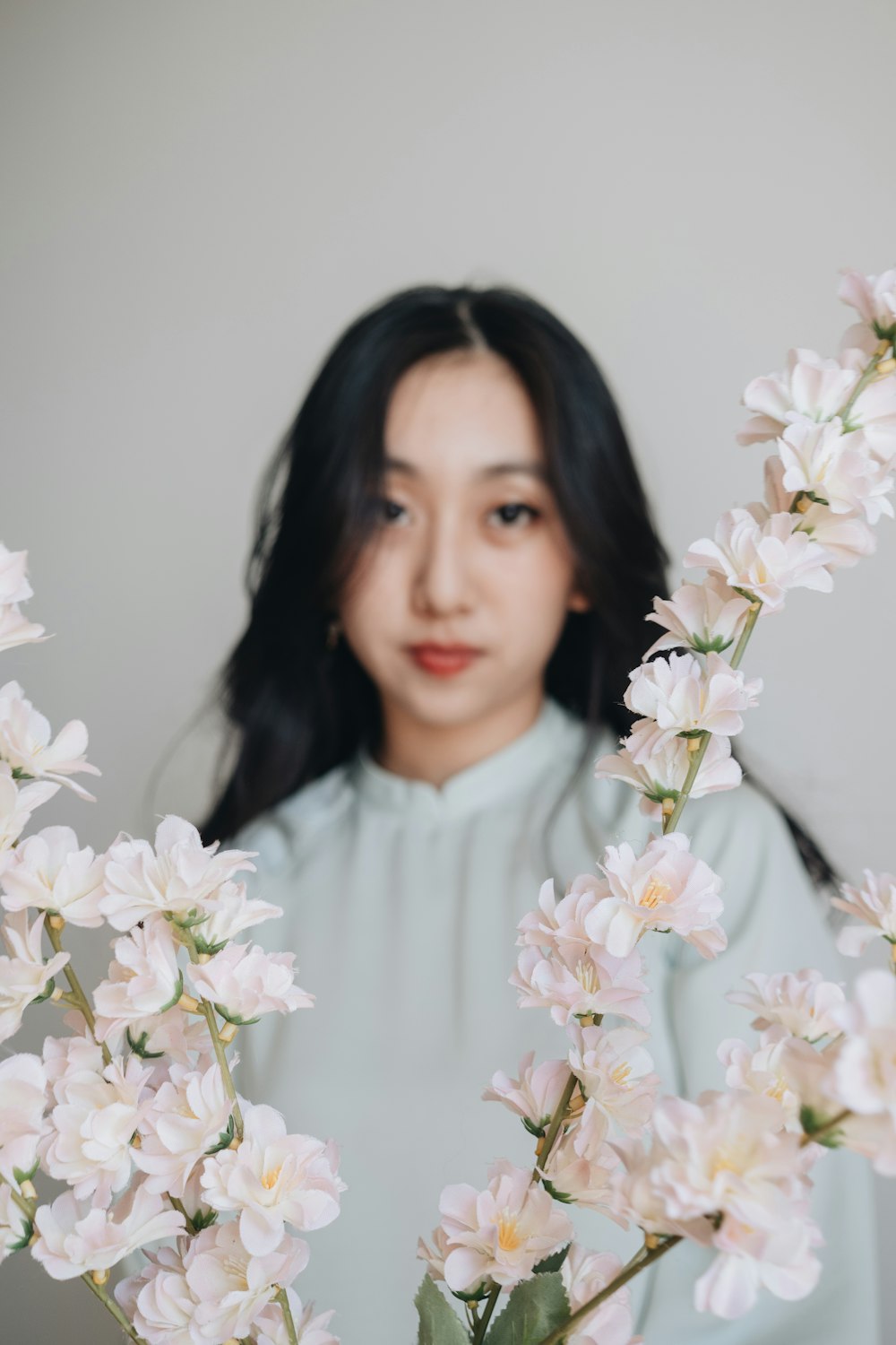 a woman standing behind a bunch of white flowers