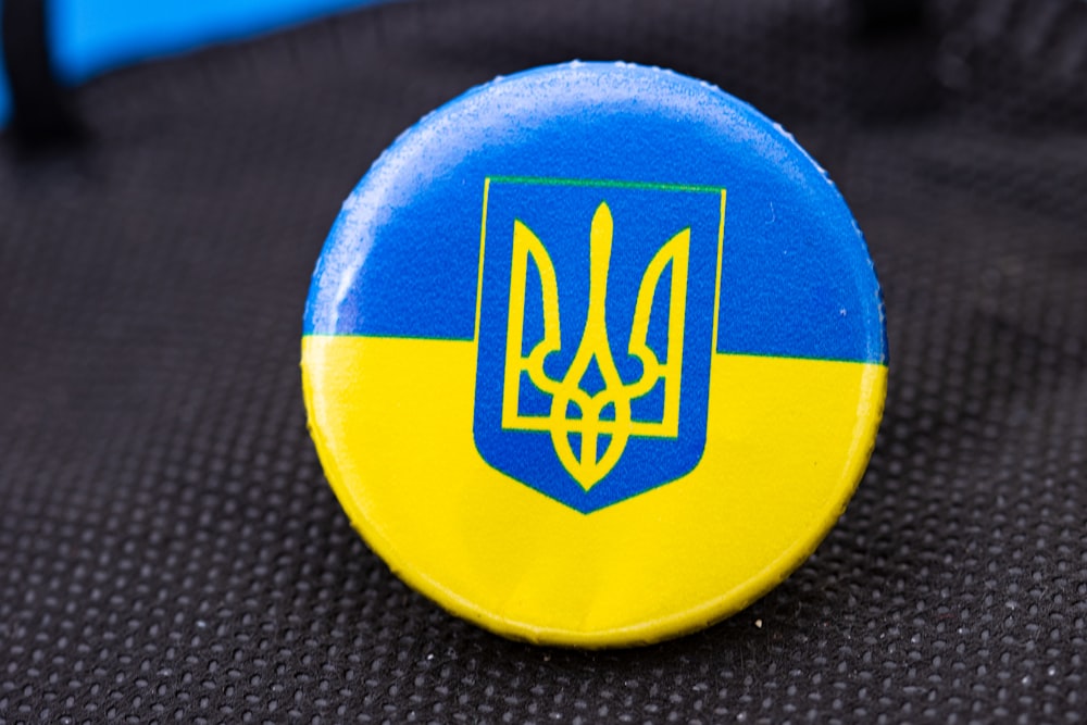 a blue and yellow button with a coat of arms on it
