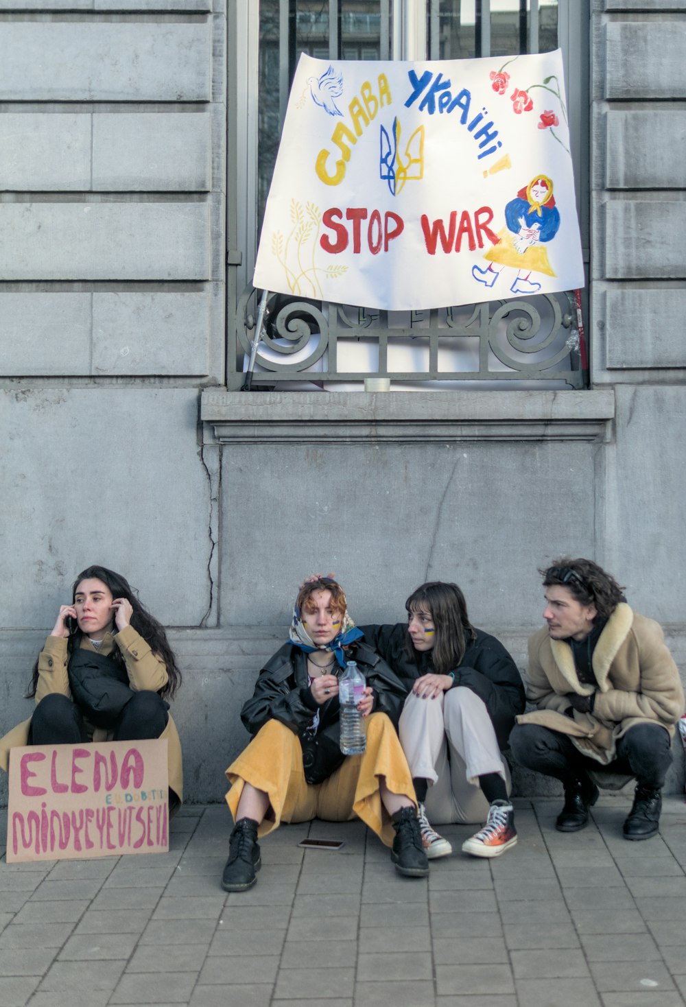 Un gruppo di persone sedute una accanto all'altra su un marciapiede