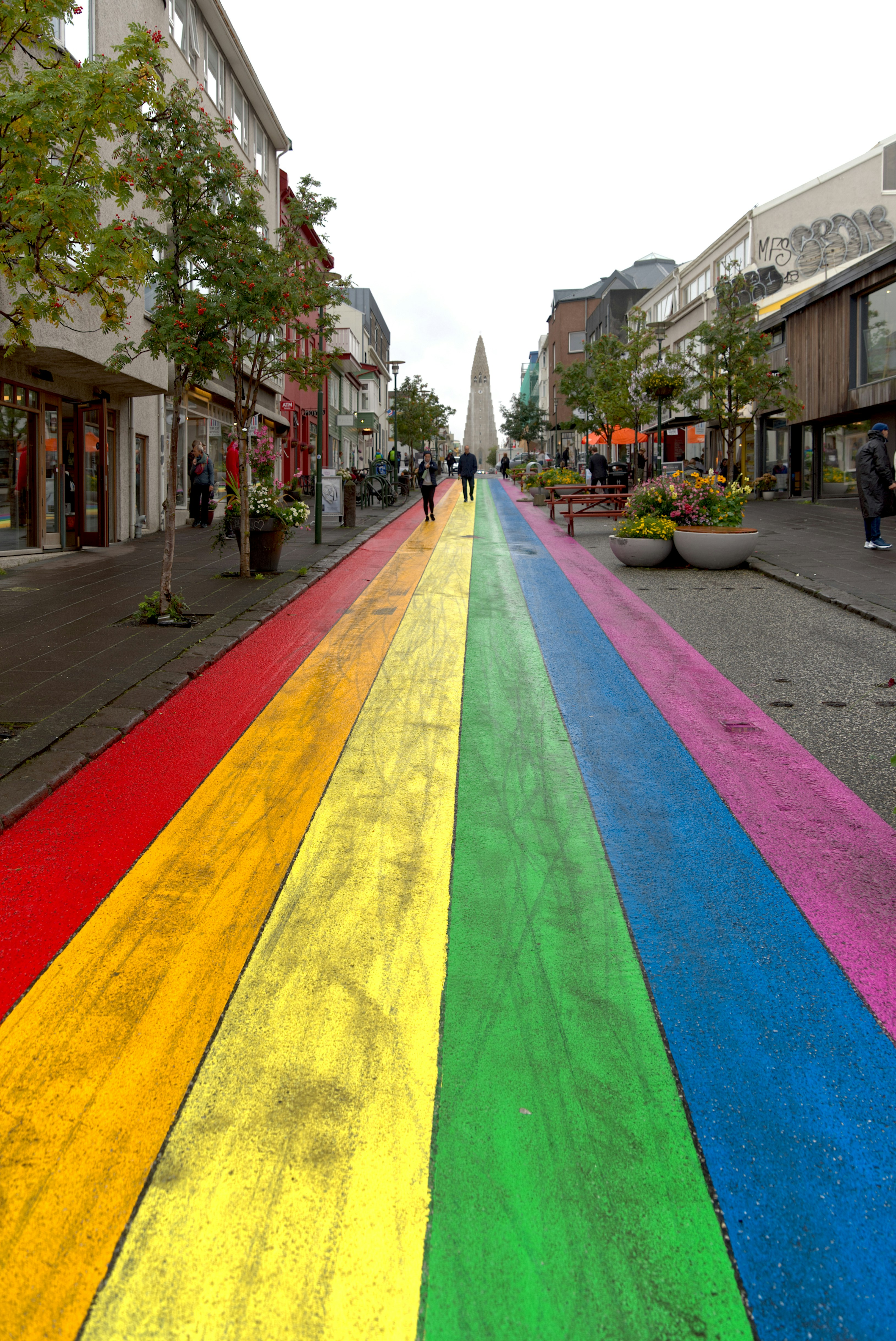 Una calle pintada de arco iris con gente caminando por ella