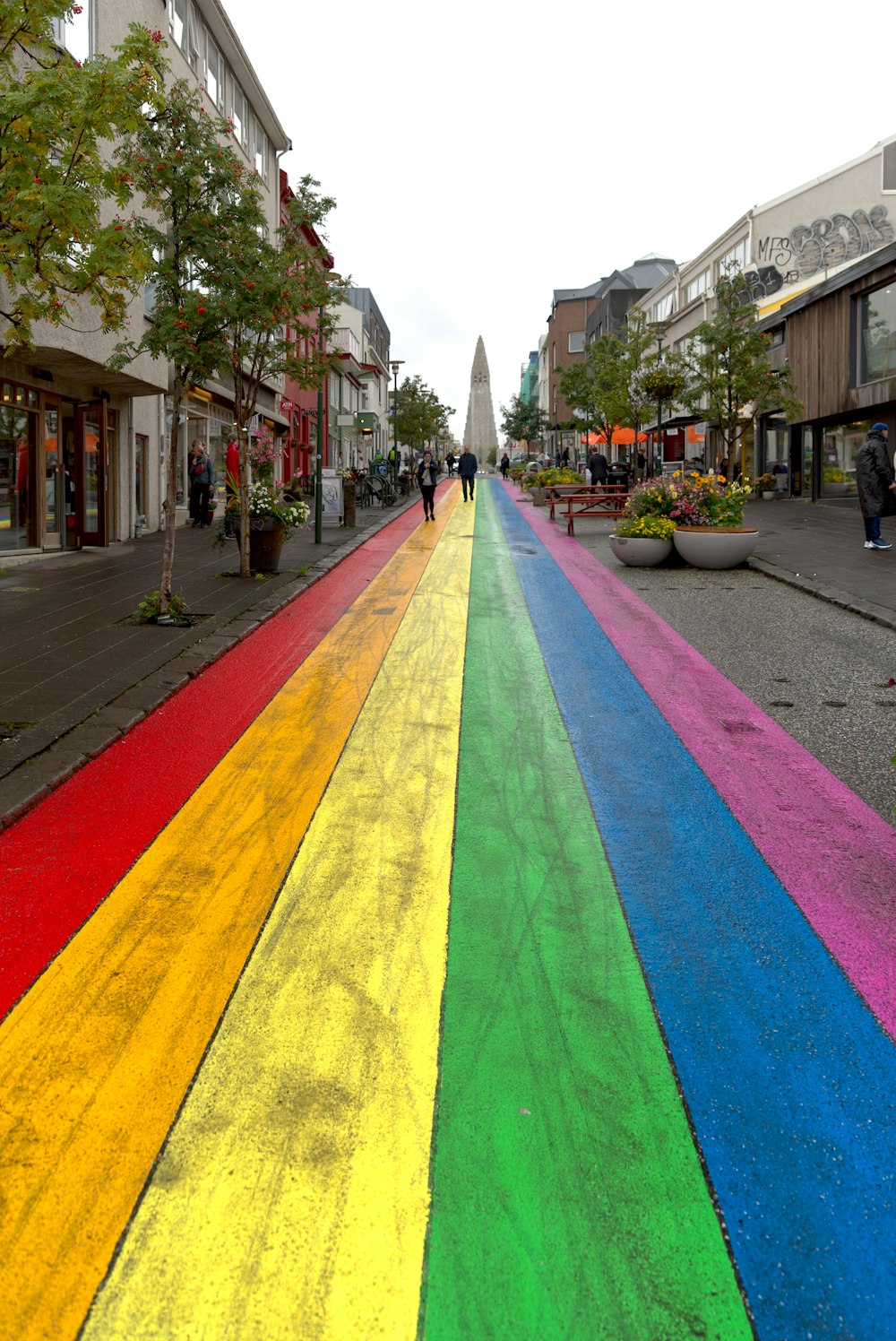 a rainbow painted street with people walking down it