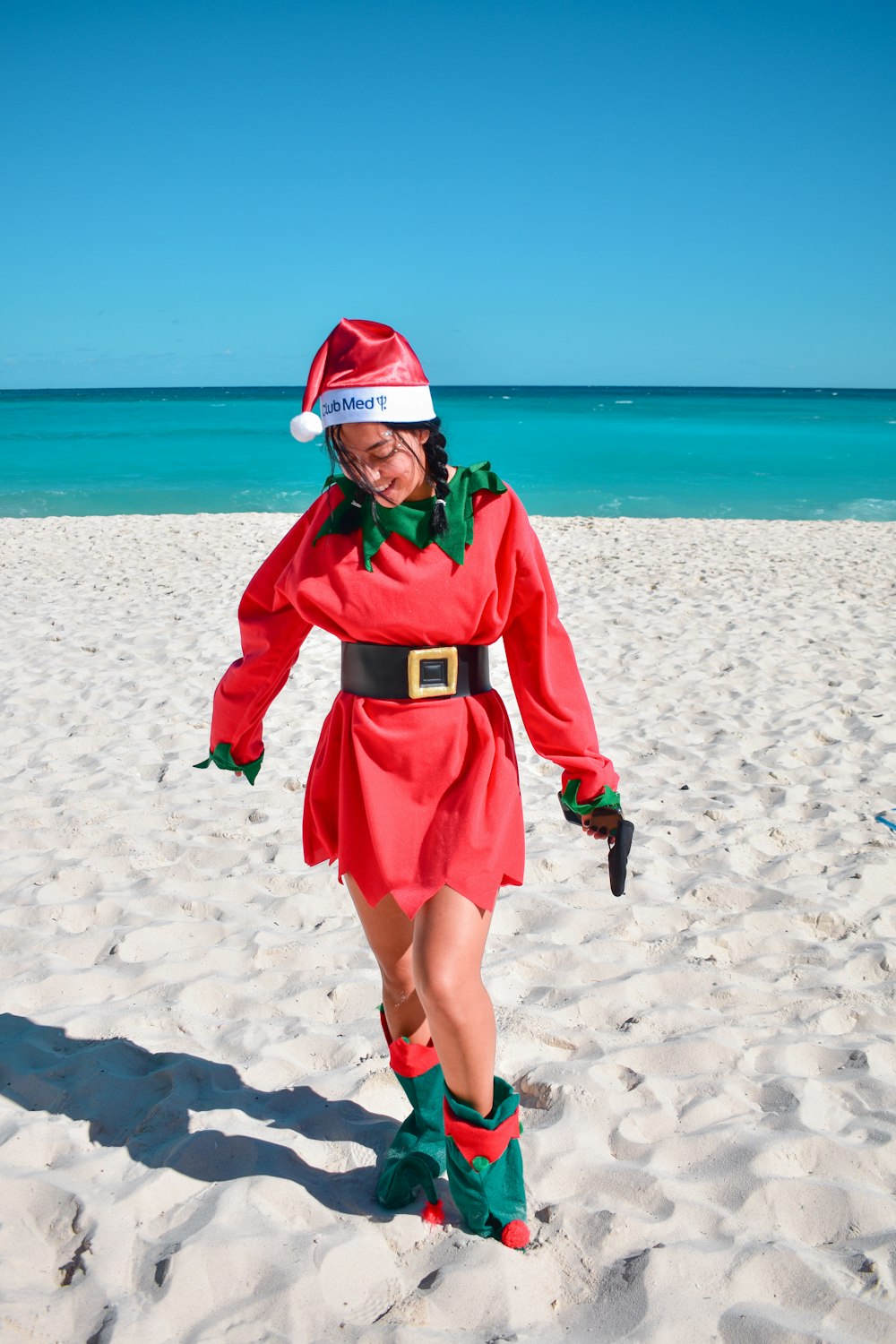 a woman in a santa claus costume on the beach