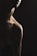 A dimly lit photograph featuring the silhouette of a person's neck and shoulder. The lighting creates a dramatic contrast between the shadowed and illuminated areas, emphasizing the contours and texture of the skin. The face is partially visible, creating a mysterious and introspective atmosphere.