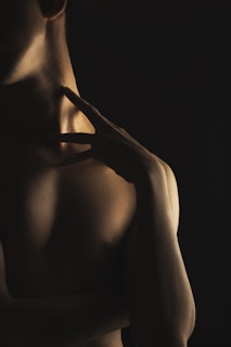 A silk robe slipping off a shoulder, with soft shadows emphasizing the curve of the neck.