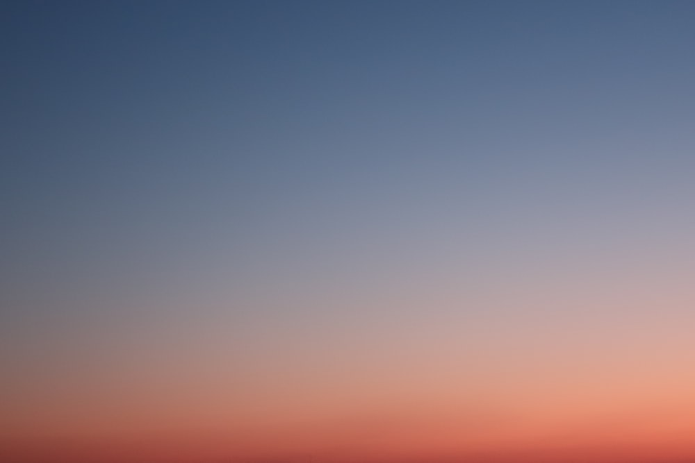 a plane flying in the sky at sunset