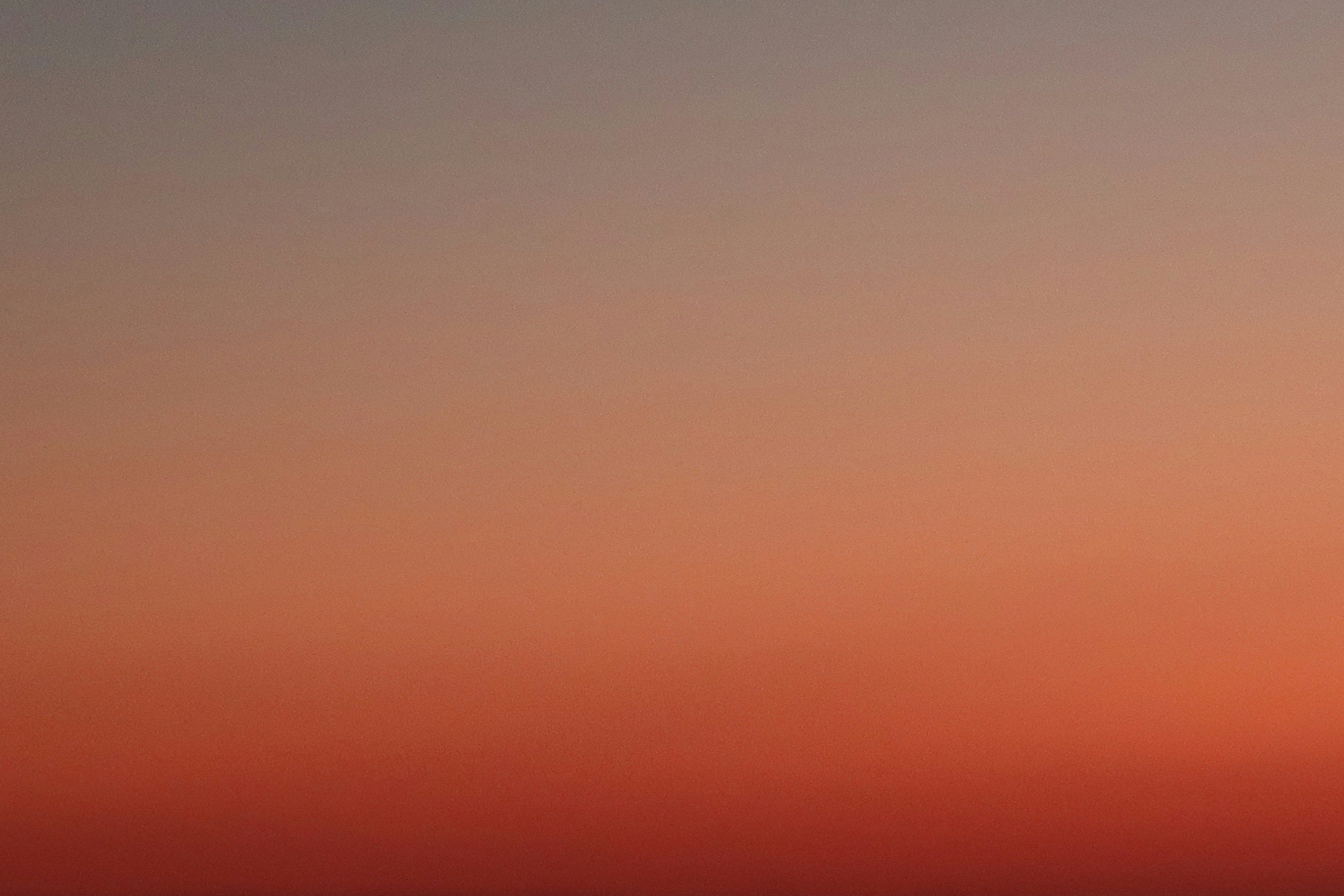 a plane flying in the sky at sunset